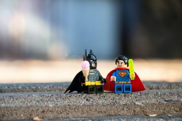 To illustrate Comiccon Montreal theme, two superhero lego characters (Batman and Spiderman) are sitting on a sidewalk holding ice cream and popsicles.