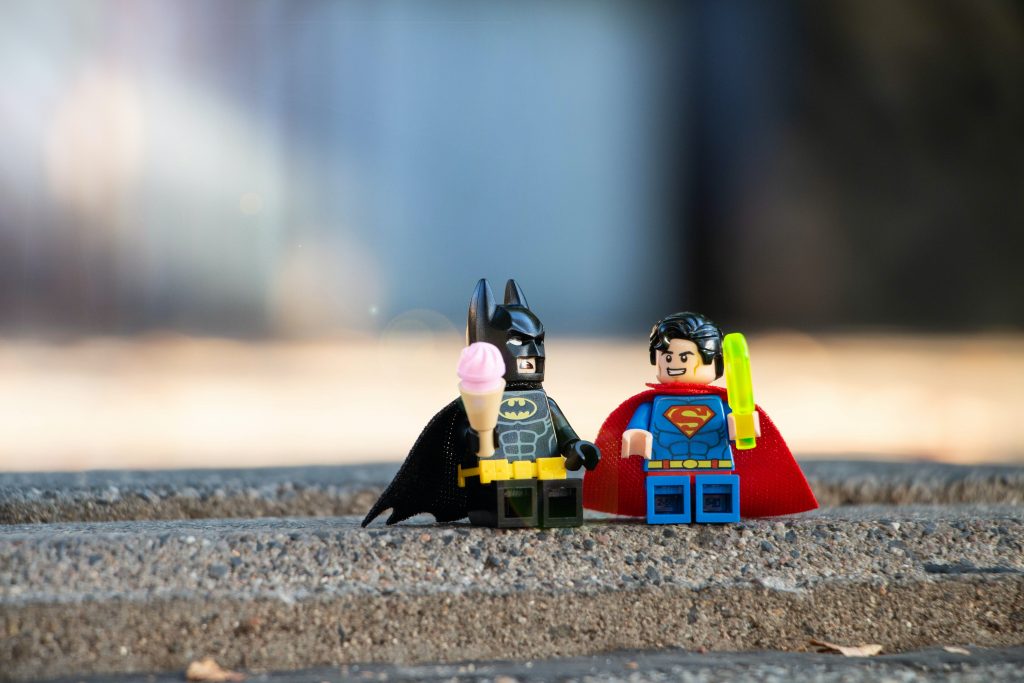 Images pour représenter le thème du Comiccon de Montréal. Deux personnages de lego, Batman et Spiderman, sont assis sur le trottoir.